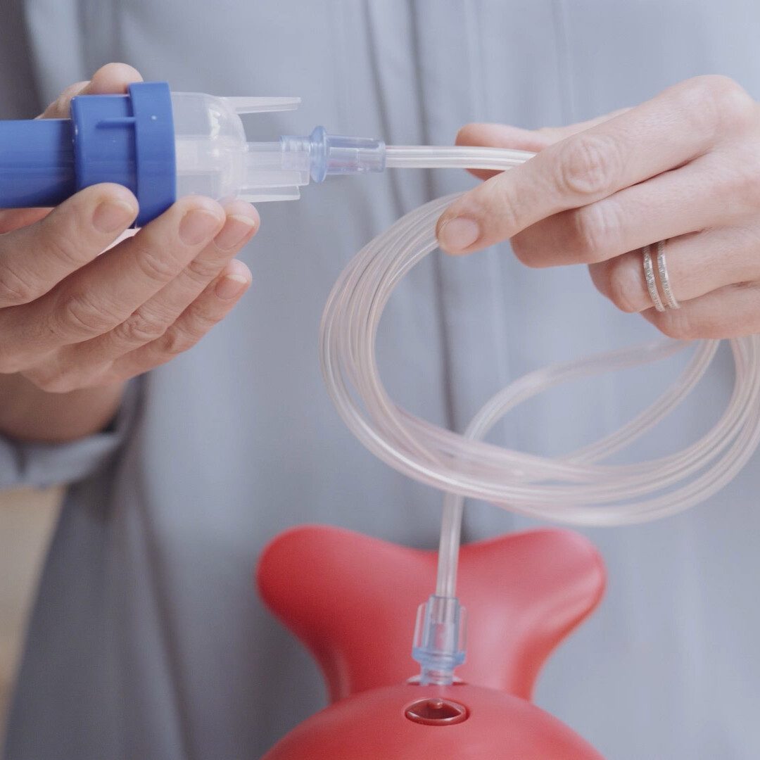 Close-up of parent gently holding Philips nebuliser product during instructional ‘How to’ video on respiratory treatment